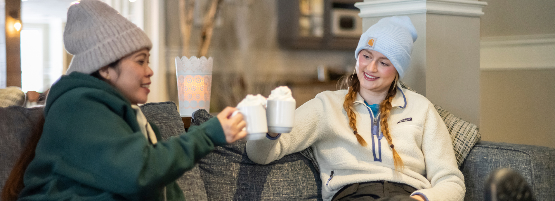 two women drinking hot chocolate by a fire